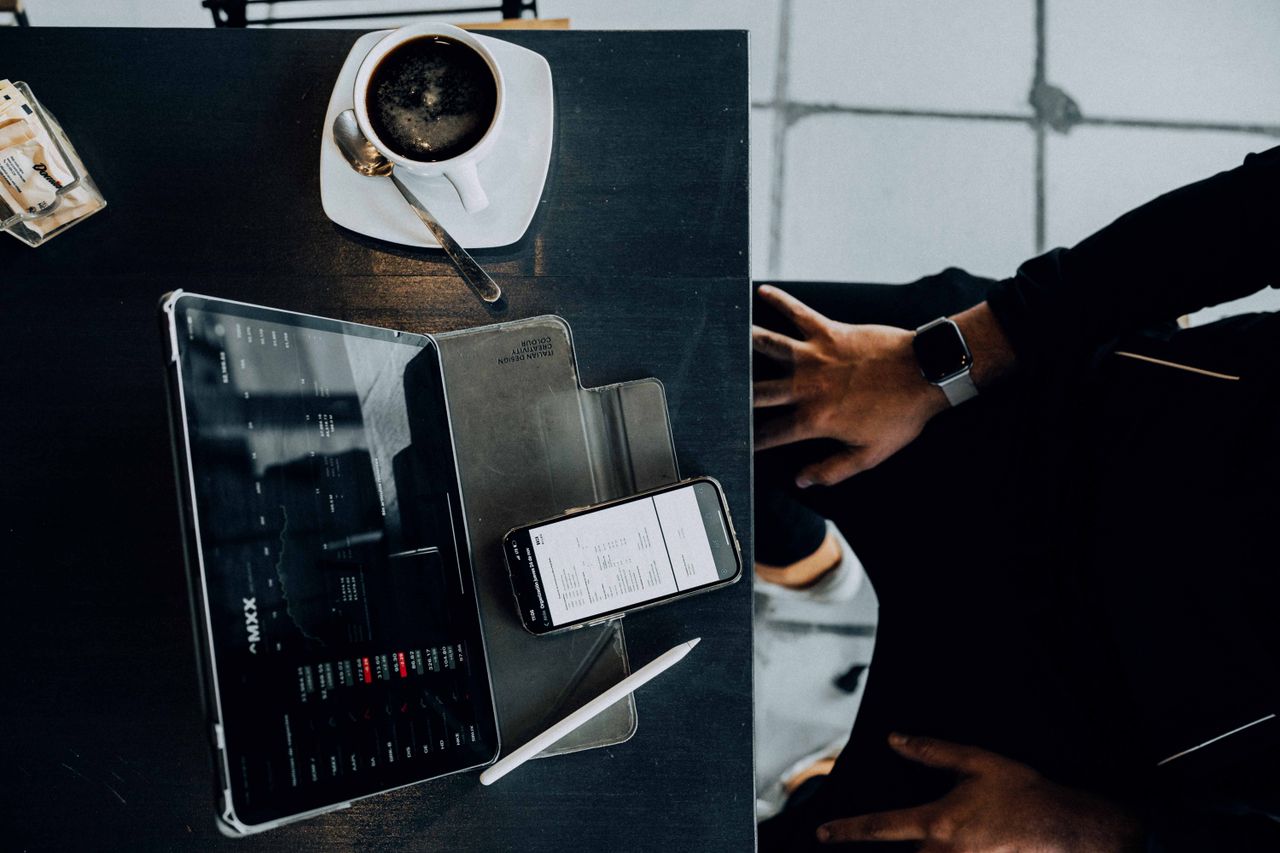Overhead shot of a modern workspace with coffee, tablet, and smartphone, emphasizing technology usage.